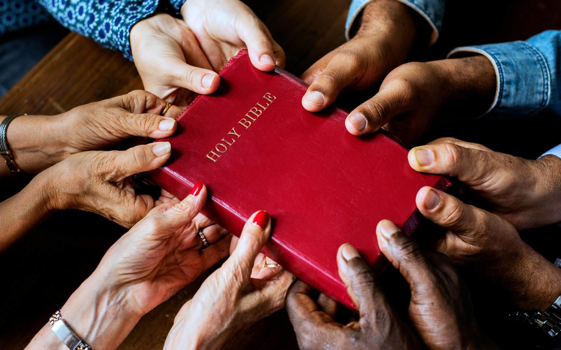 viele-haende-halten-die-bibel