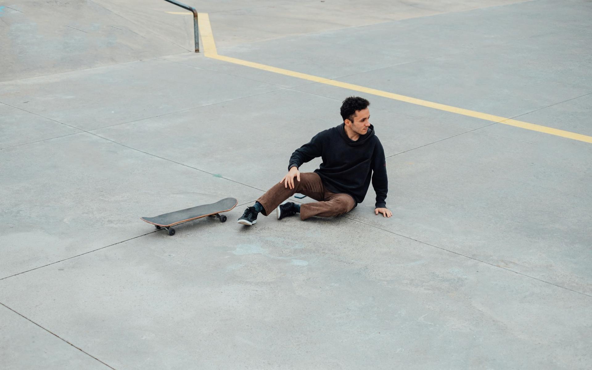 Mann der vom Skateboard gefallen ist