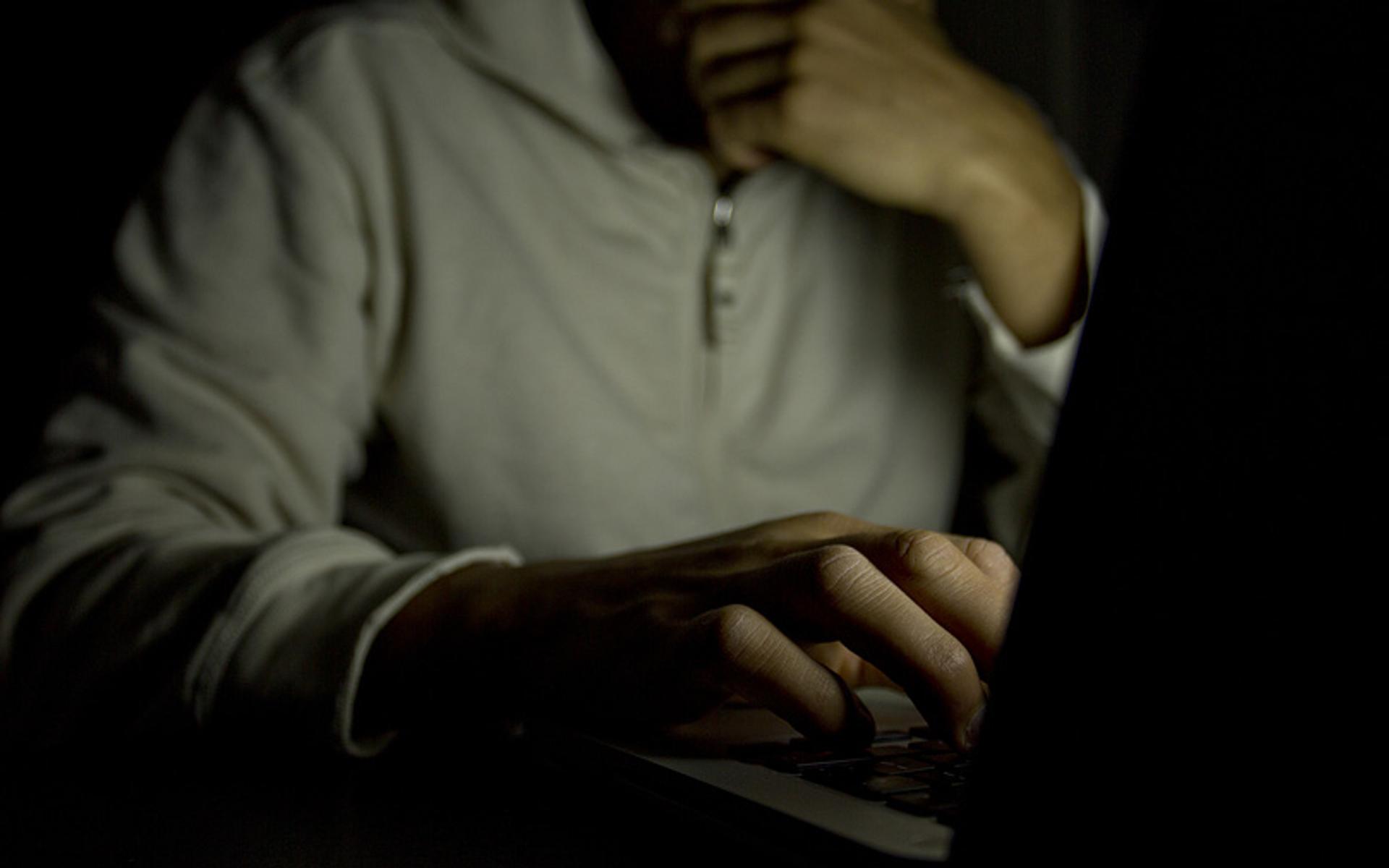 Mann versteckt und alleine vor dem Laptop (Symbolbild)