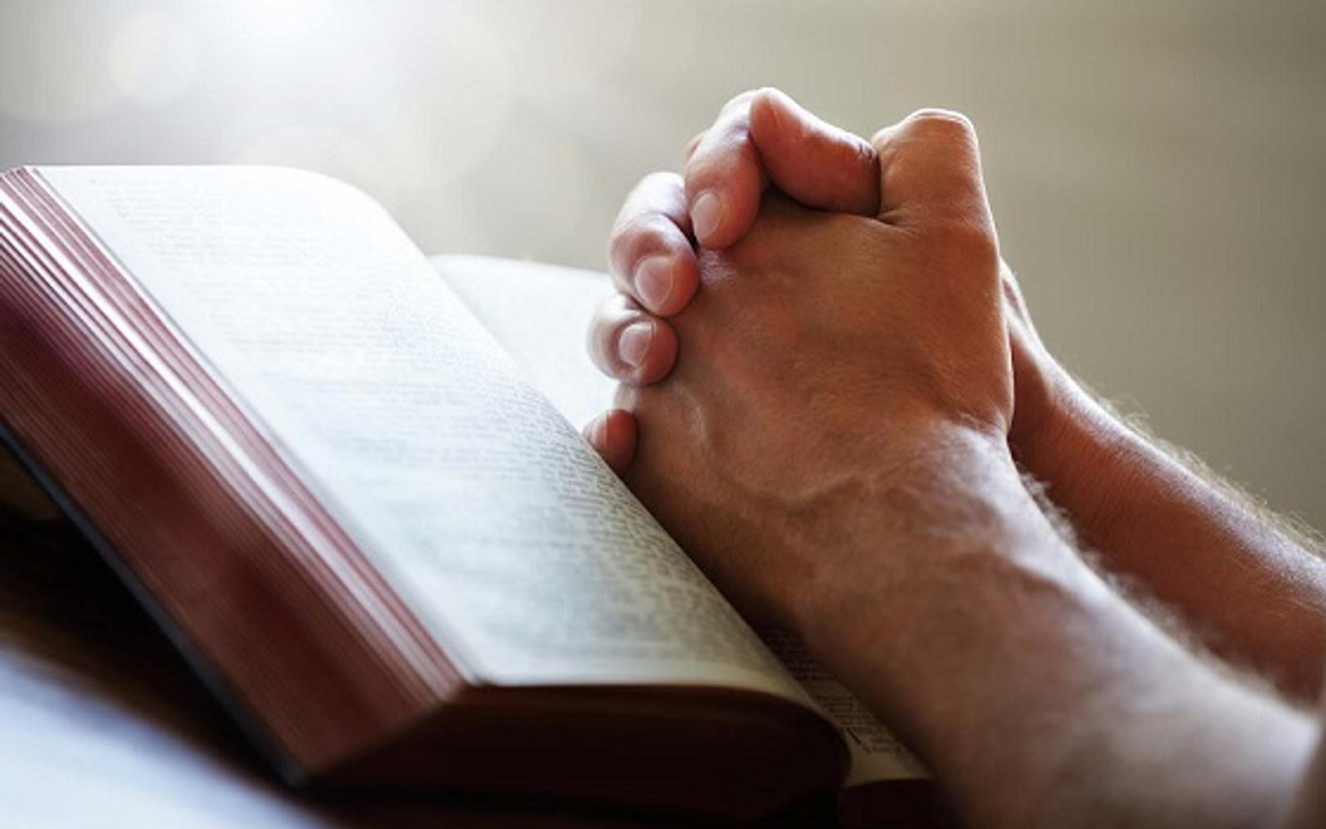 betende Hände auf Bibel