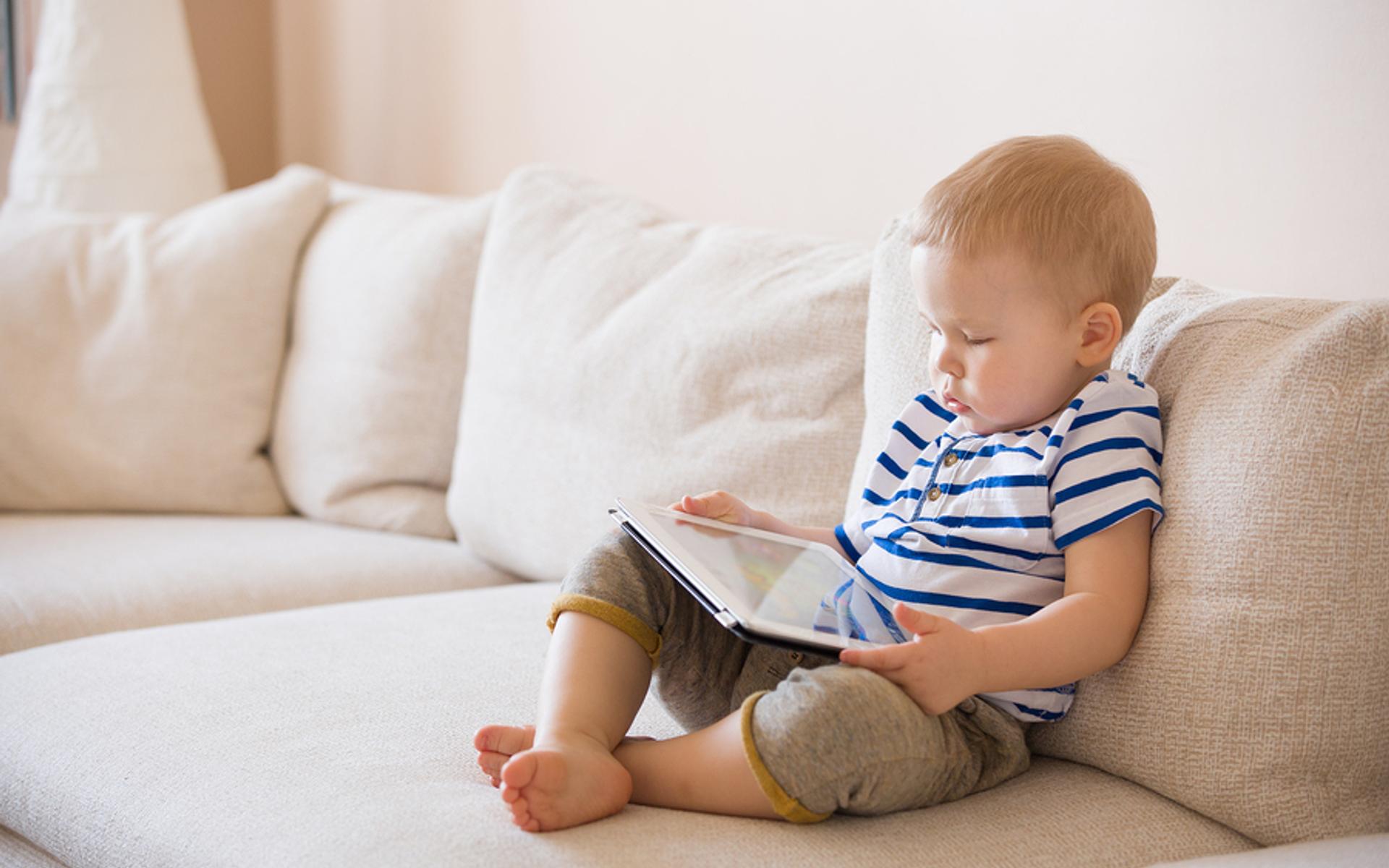 Kleinkind mit Tablet auf Sofa
