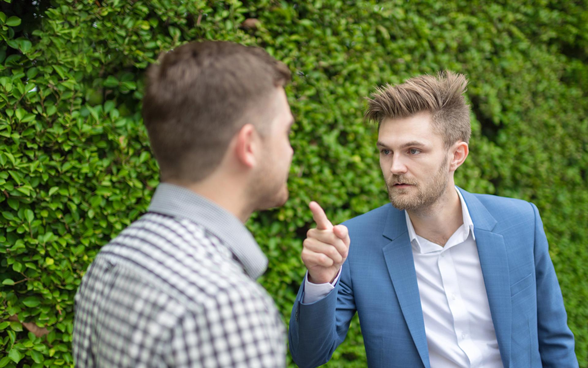 Mann zeigt mit dem Zeigefinger auf anderen Mann.