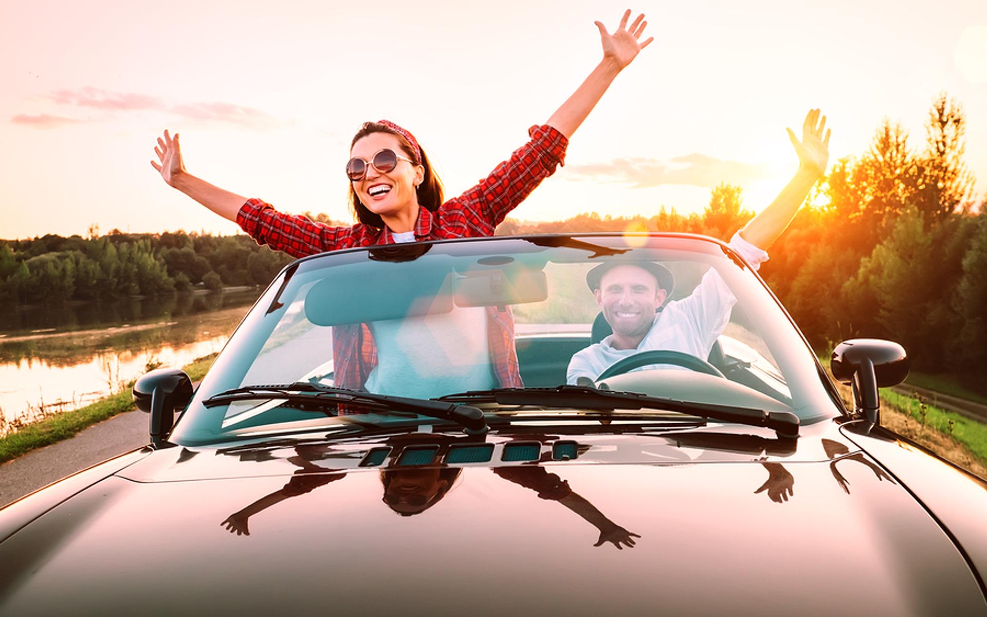 Ein Paar feiert ausgelassen im Cabriolet (Symbolbild)