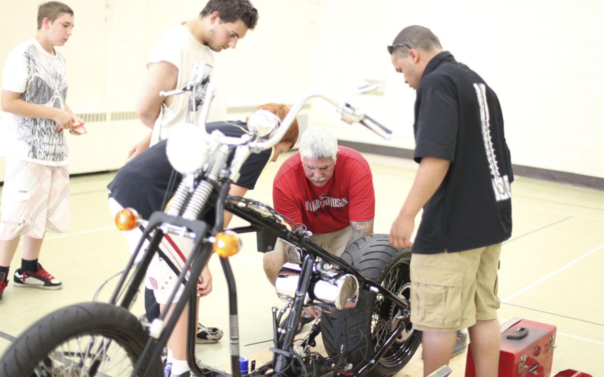 Rick Osbourne arbeitet mit Jugendlichen an einer Harley-Davidson