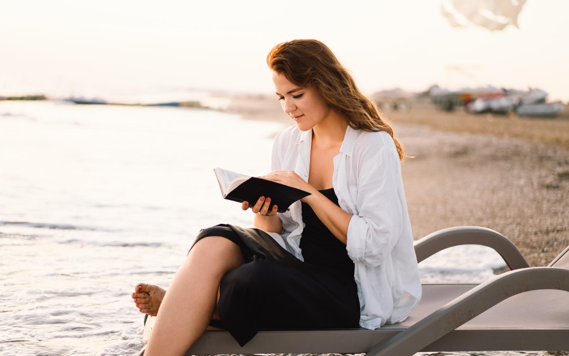 Frau liest die Bibel am Strand