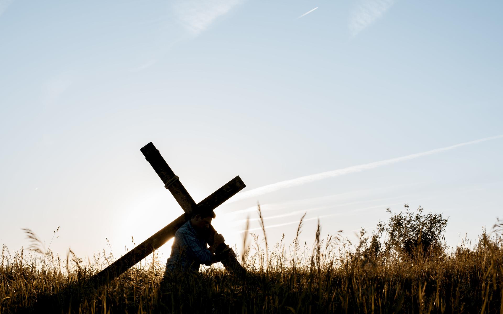Mann trägt Kreuz auf dem Rücken