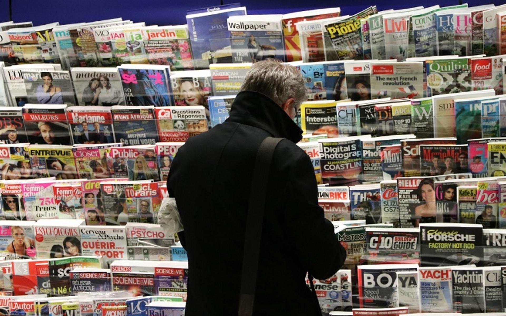 Ein Mann sucht eine Zeitung unter einer riesigen Auswahl.