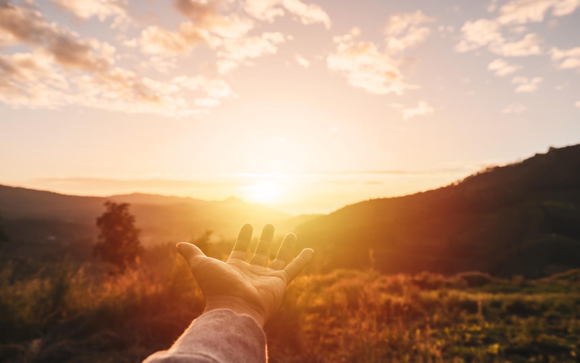 Eine Hand streckt sich aus in Richtung des Himmels