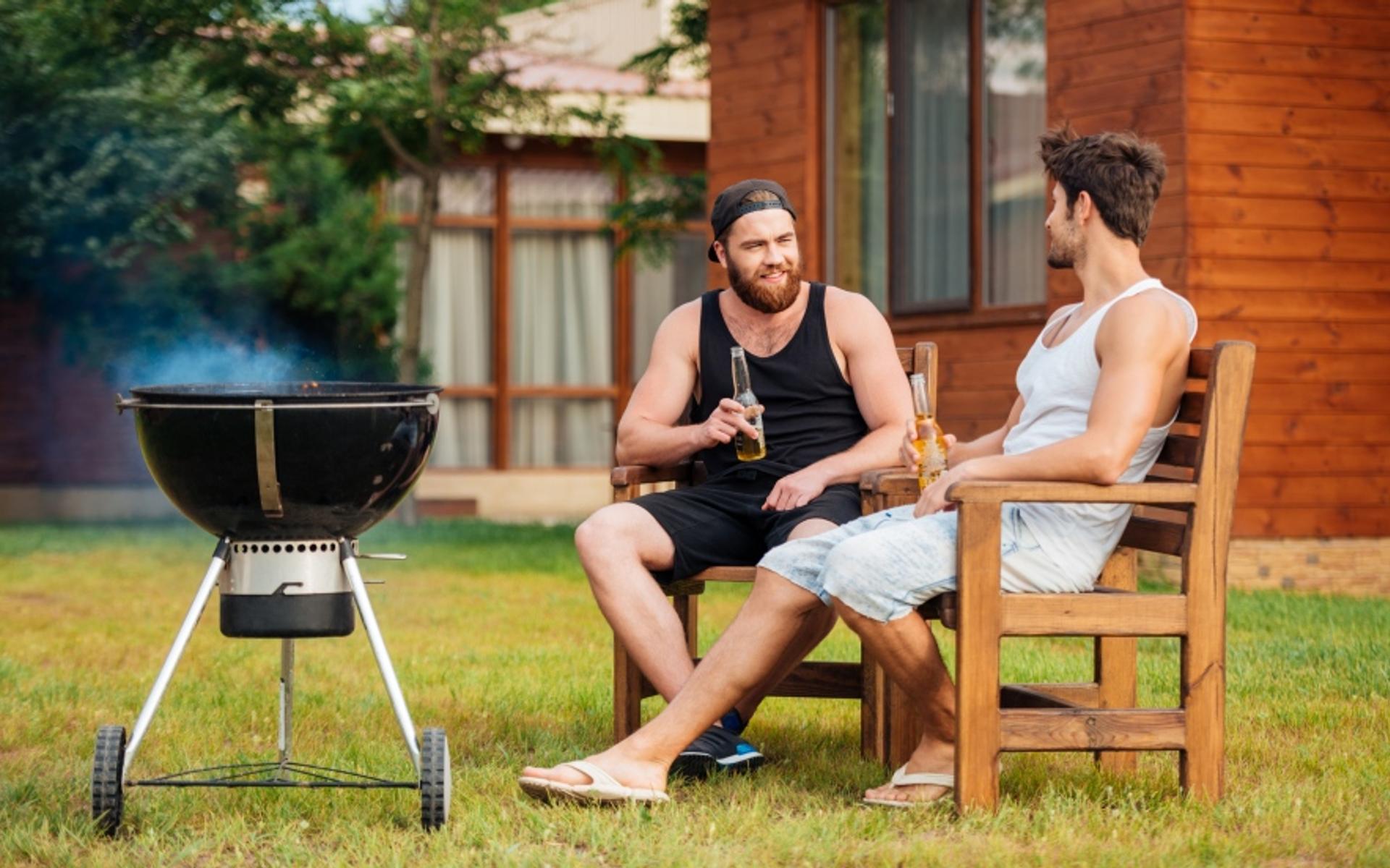 Zwei Männer pflegen die Freundschaft beim Grillieren.