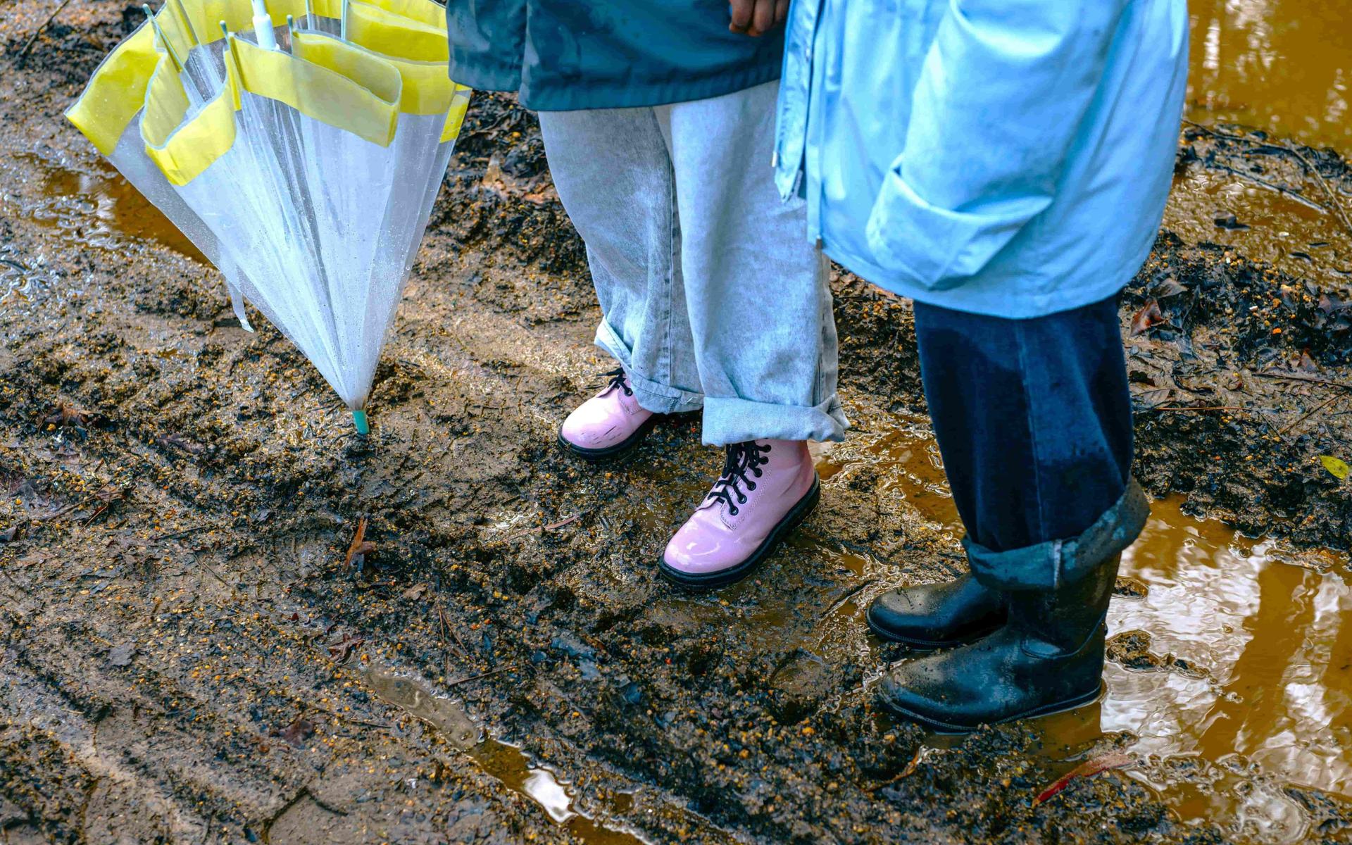 zwei-personen-stehen-im-schlamm-und-halten-regenschirme-in-der-hand
