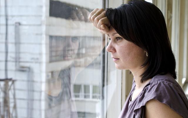 Frau blickt besorgt aus dem Fenster