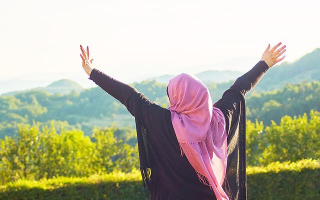 Verschleierte Muslime mit ausgestreckten Armen in der Natur