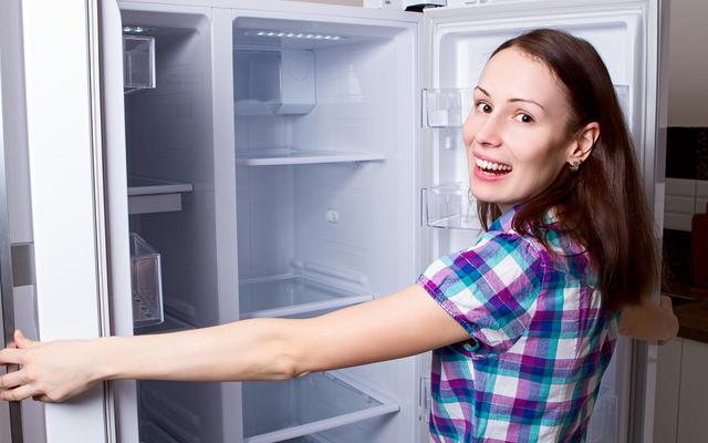 Frau vor leerem Kühlschrank