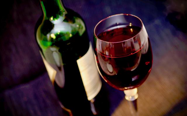 Ein Glas Wein mit der Flasche nebendran