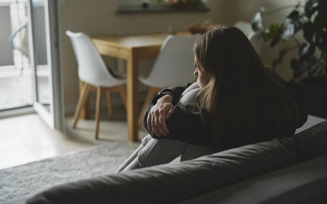 Frau sitzt alleine im Wohnzimmer