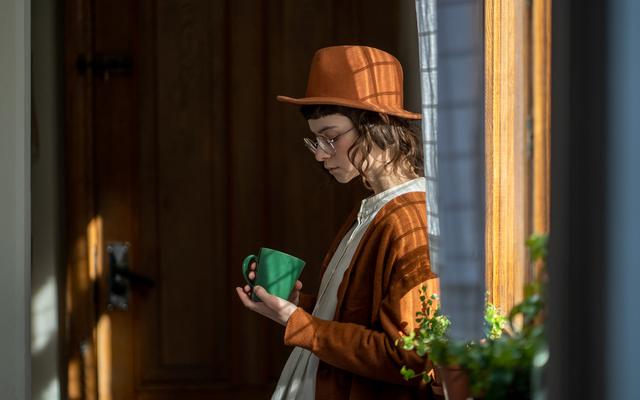 Mädchen steht nachdenkend neben einem Fenster