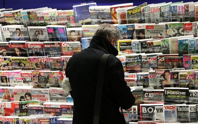 Ein Mann sucht eine Zeitung unter einer riesigen Auswahl.