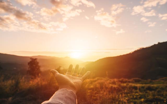 Eine Hand streckt sich aus in Richtung des Himmels