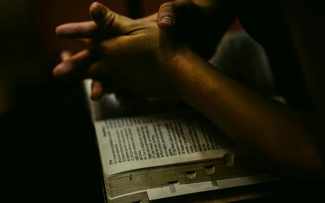 Betende Hände auf einer offenen Bibel