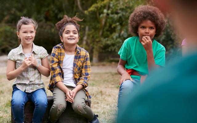 Kinder hören ihrem Leiter bei einem Input zu (Symbolbild)