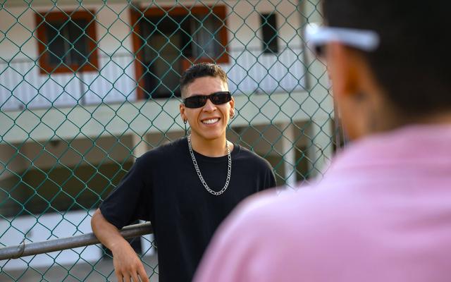 ein-mann-mit-sonnenbrille-der-neben-einem-zaun-steht